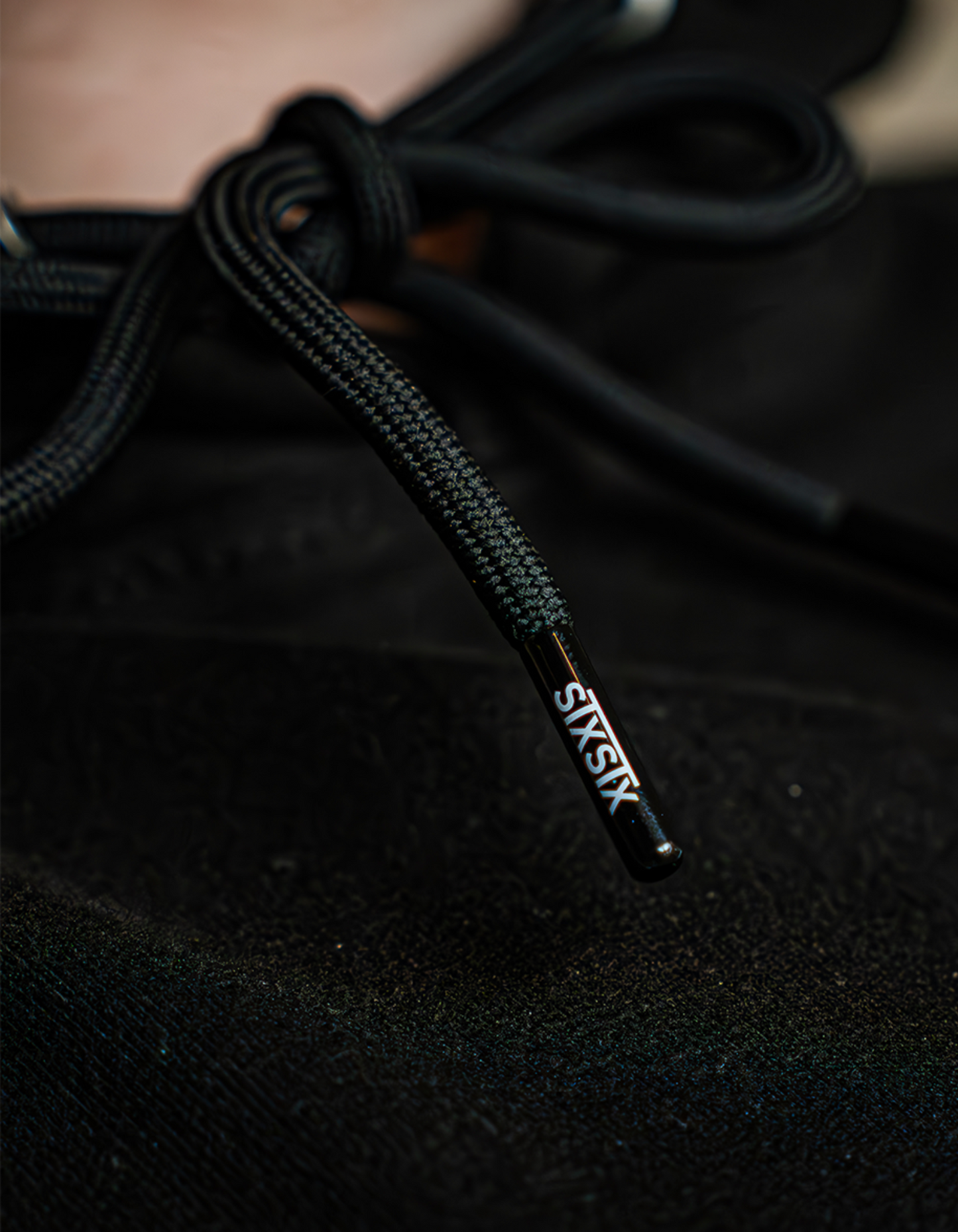 Close-up of black Hoodie String with 'STXSTX' branding on a dark background