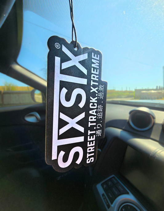 An air freshener with the logo 'STXSTX' and text saying street track xtreme hanging on a rear view mirror inside a nissan 370z car