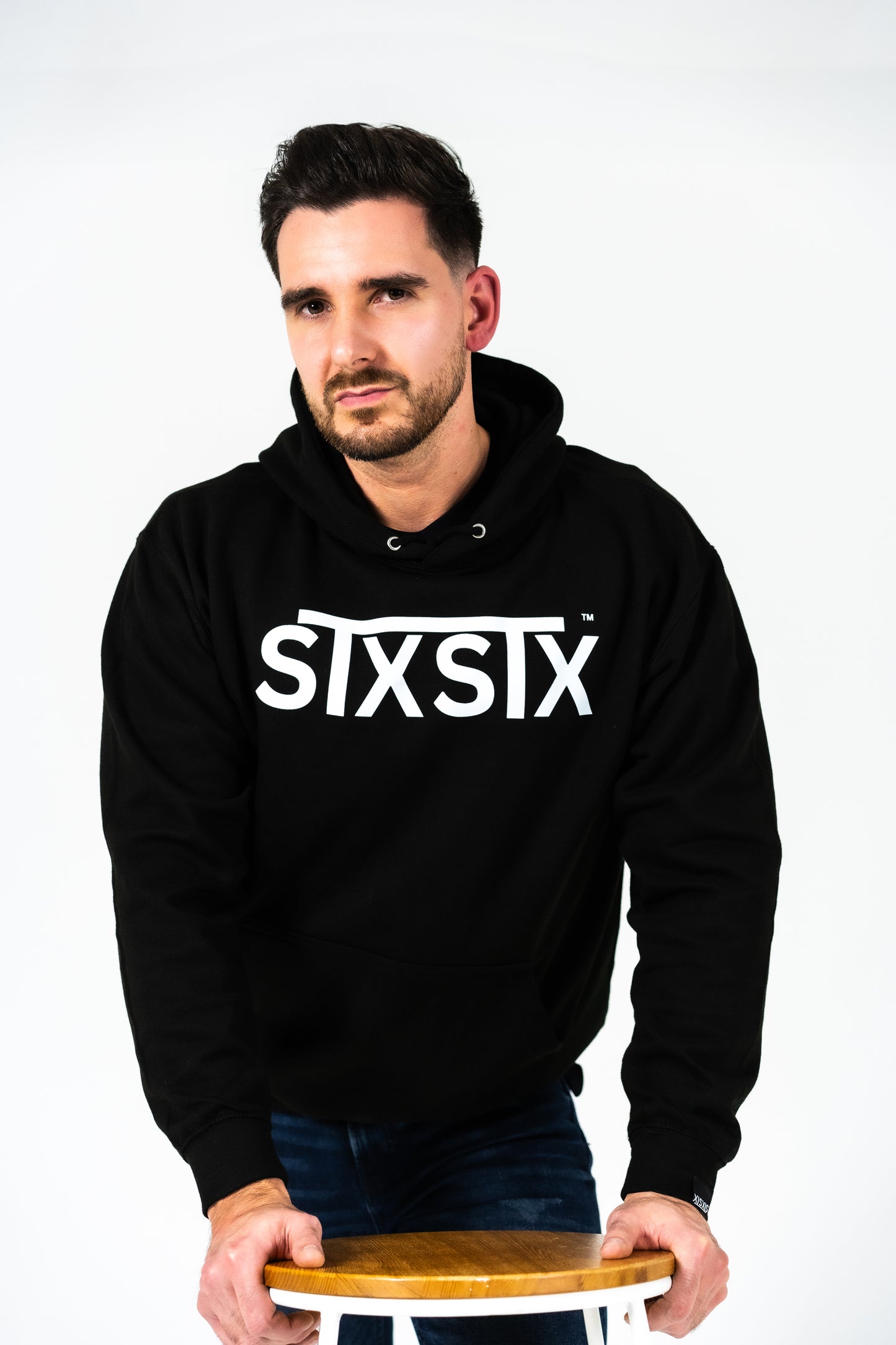 Man wearing a black hoodie with 'STXSTX' logo on a white background