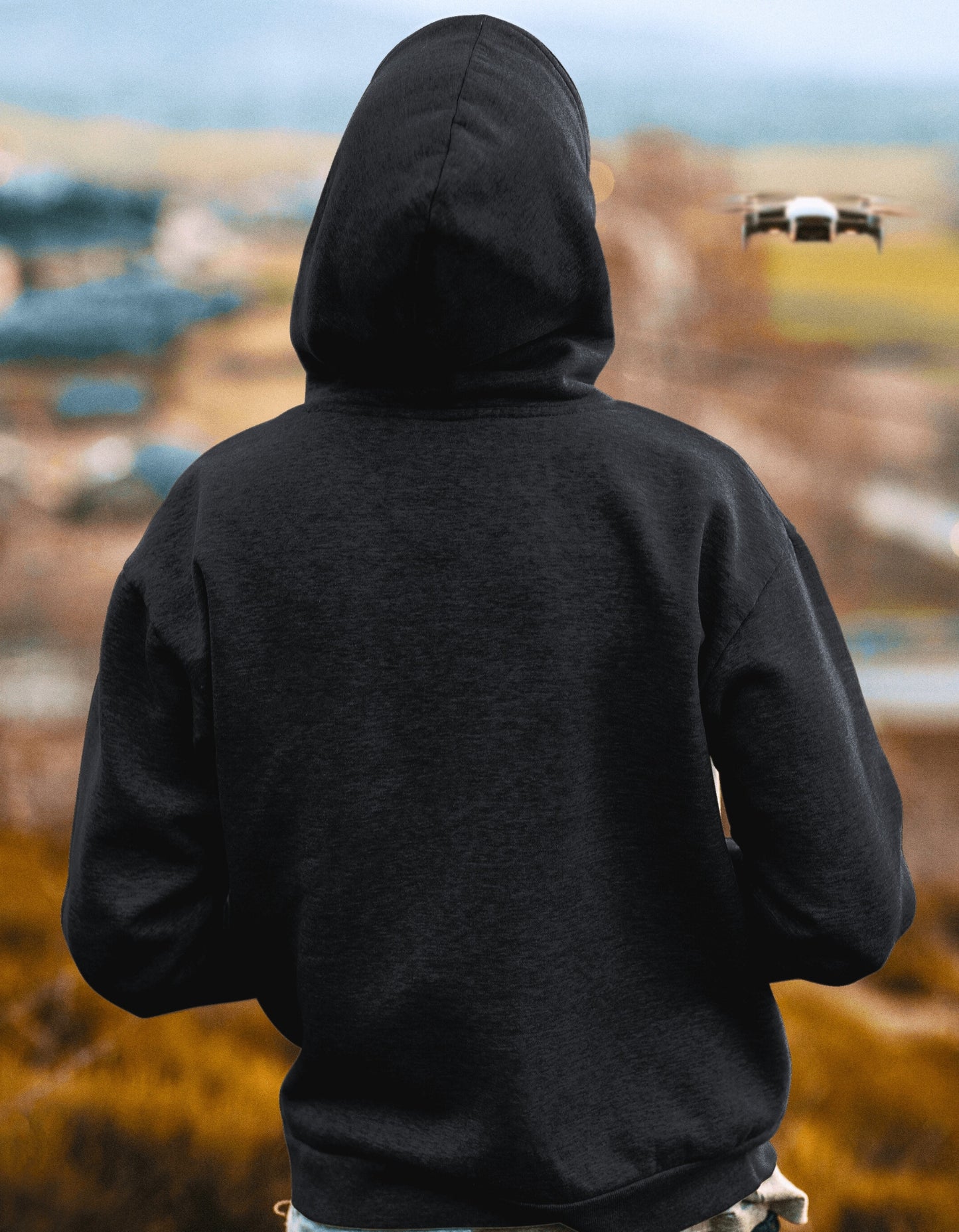 Person wearing a black hoodie with a blurred outdoor background