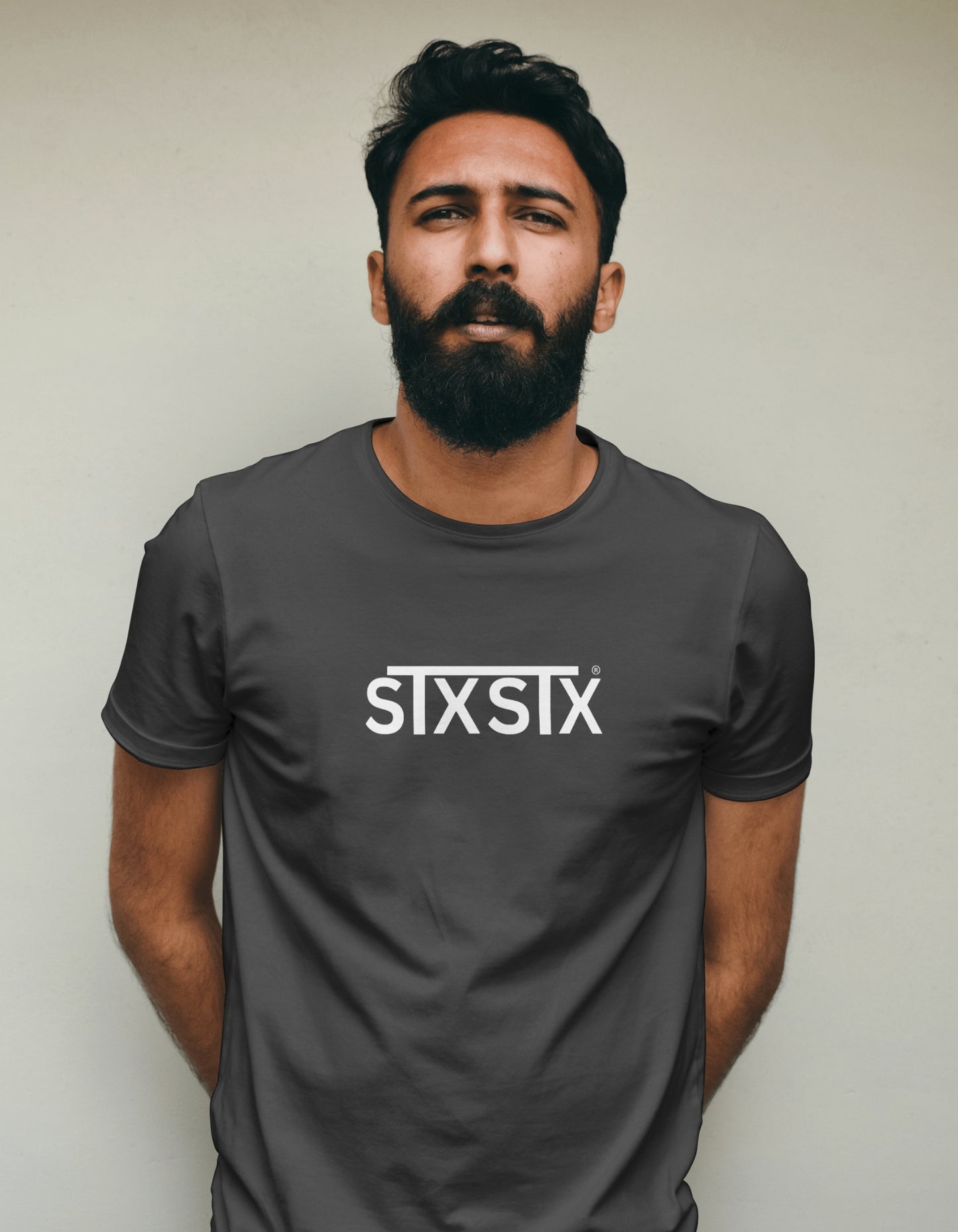 Man wearing a dark gray t-shirt with 'STXSTX' logo against a plain background