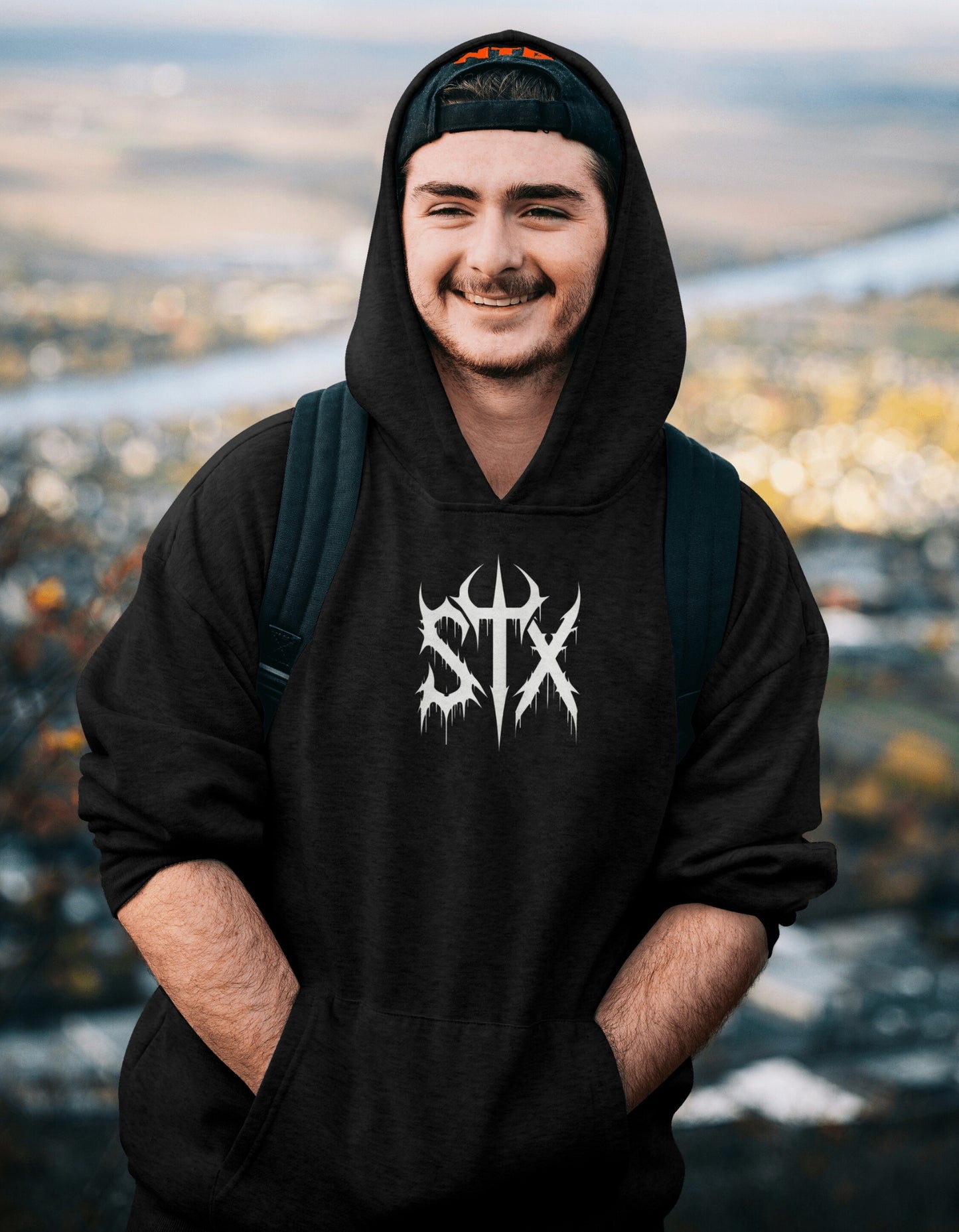 Person wearing a black hoodie with 'STXSTX' logo against a blurred natural background