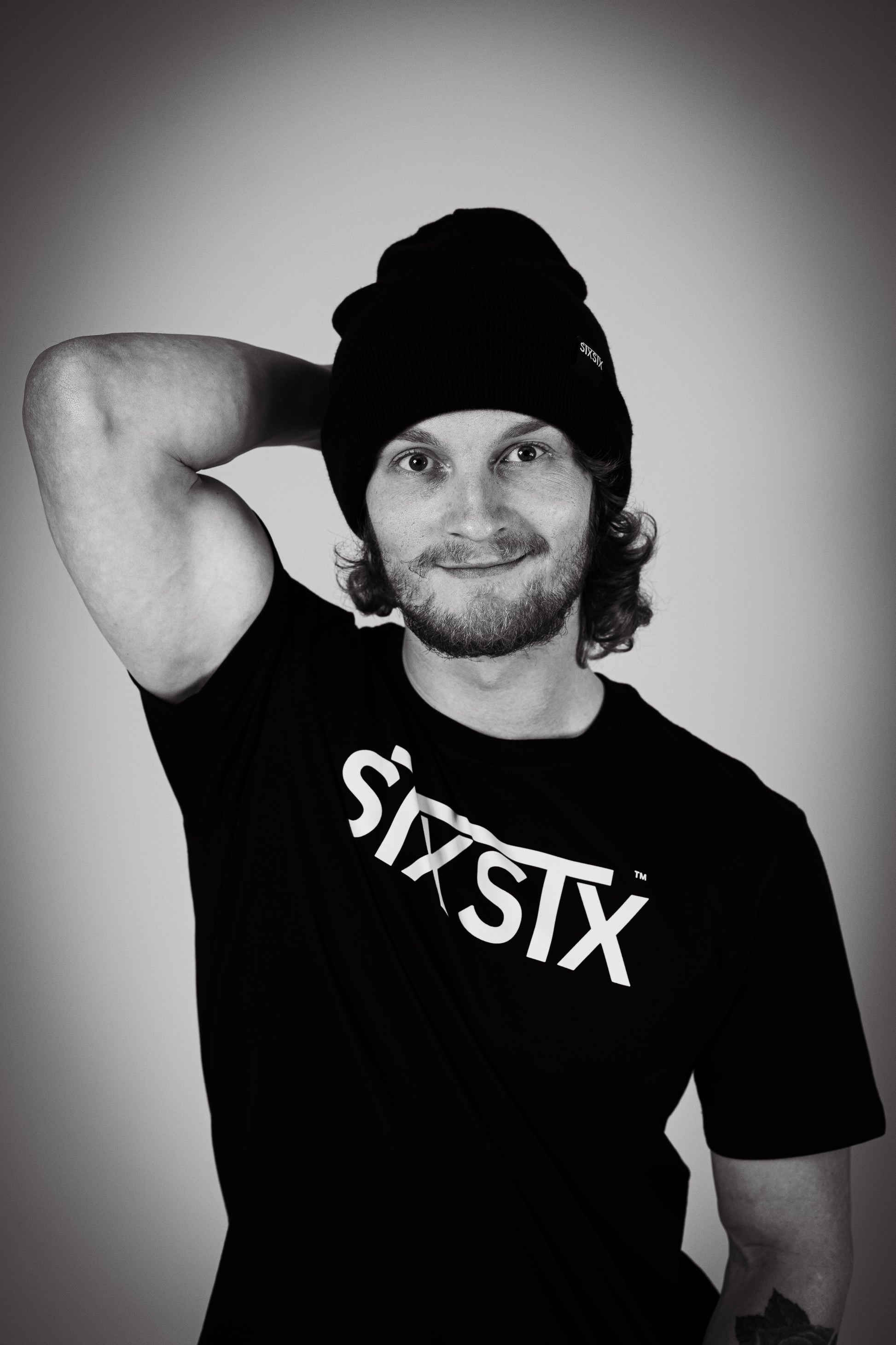 Man wearing a black tshirt with STXSTX logo in bold. also he is wearing a black STXSTX beanie