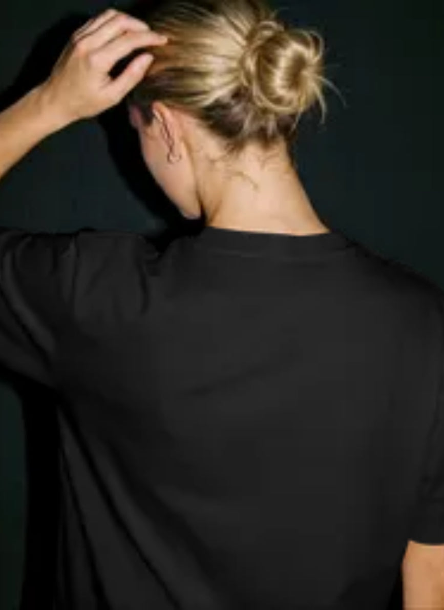 female model wearing a premium black stxstx tshirt rear view