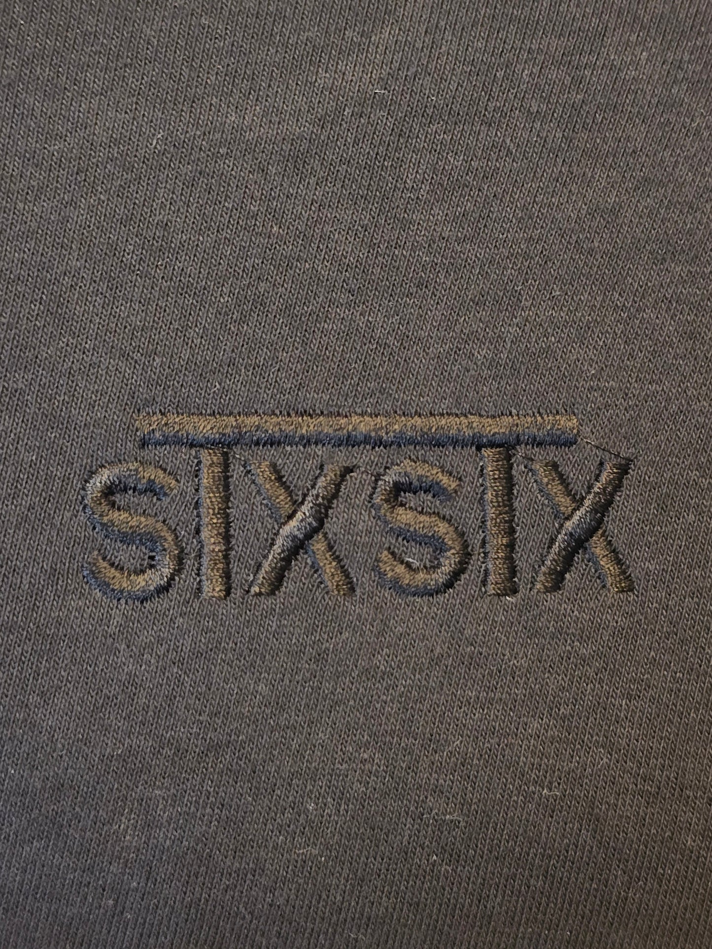 A close up of a premium black stxstx embroidered logo on a premium black hoodie