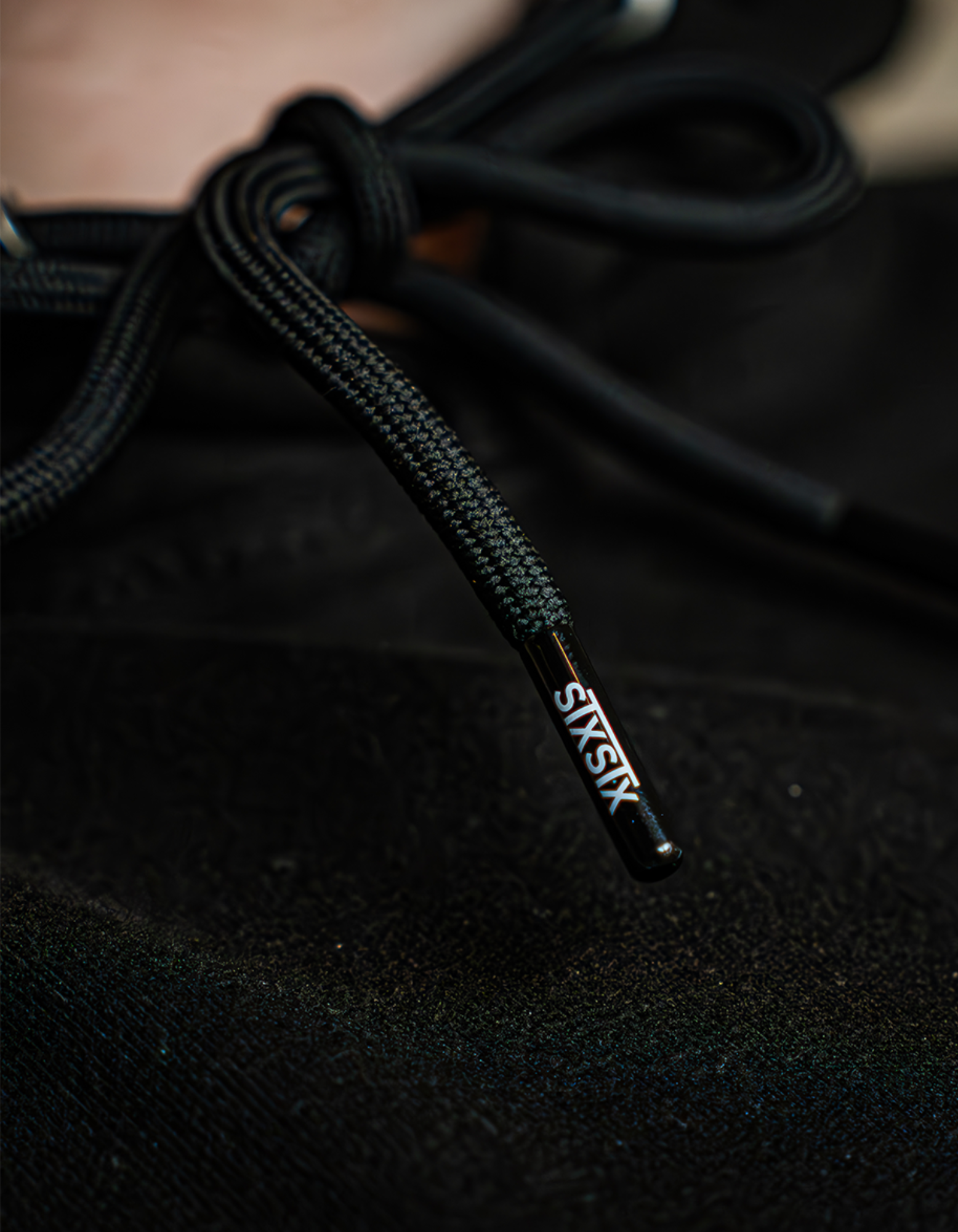 Close-up of a premium black Hoodie String with 'STXSTX' branding on the tip, showcasing the high quailty small details. 