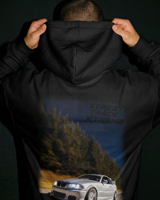 Black premium stxstx hoodie with a bmw e46 drift car graphic and 'Street Track Xtreme' text on the back, worn by a person grey background.